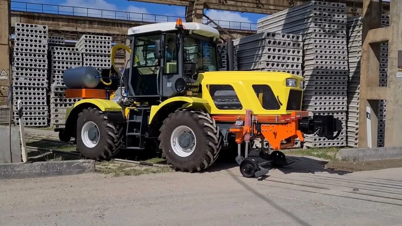 Жёлтый тягач КРТ-1 в профиль на заводской площадке, направляющие катки комбинированного хода опущены к рельсу